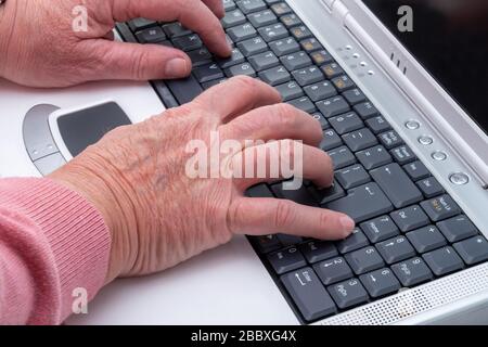 An elderly mans hands on a computer keyboard Stock Photo