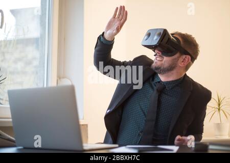 businessman finishes his work and taking virtual reality goggles on by window black table with notebook papers phone VR Stock Photo