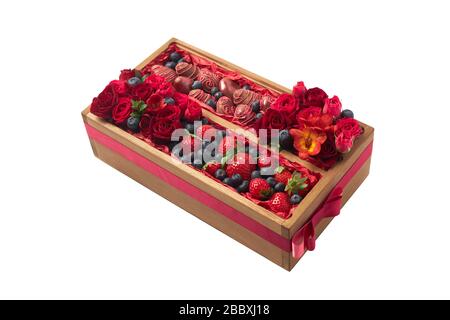 Original gift in the form of a wooden box filled with ripe chocolate covered strawberries, blueberries and red flowers on a white background Stock Photo