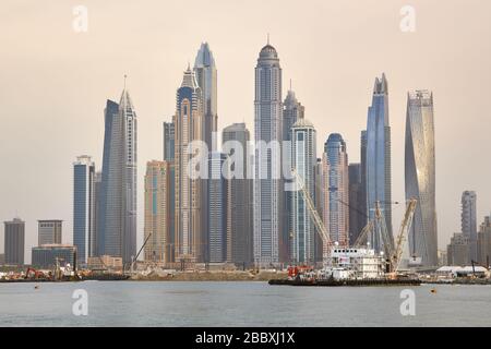 Dubai, UAE, January 13, 2019: Accommodation barge, crane barges and other ships are building a pier against the backdrop of skyscrapers at sunset Stock Photo