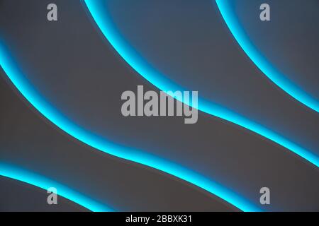 Curved lines of blue backlight on a dark background as a backdrop. Stock Photo