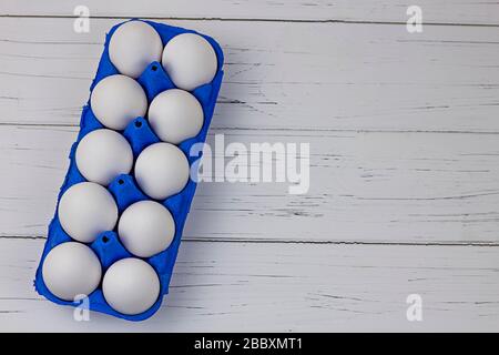 ten white eggs in blue uniform on a wooden light background Stock Photo