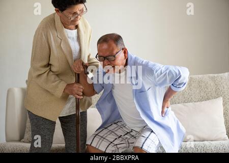 Asian old woman helping an elderly man having a back pain, backache at home. Senior healthcare concept. Stock Photo