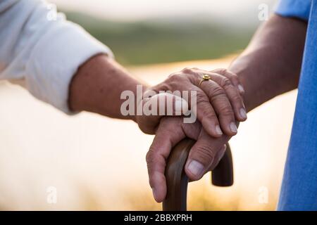 A happy senior couple asian old man and woman hold hand each other and standing in summer near mountain and lake during sunrise or sunset . Senior hea Stock Photo