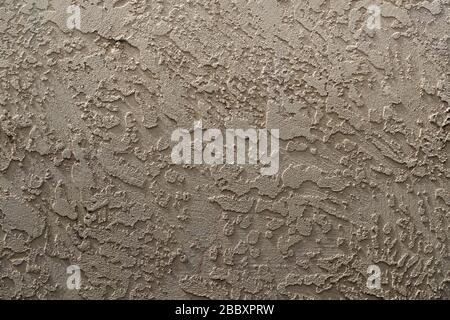 Beige stucco on a cement wall, applied in a raised splash pattern that has been troweled smooth. Provides visual interest: good for background. Stock Photo