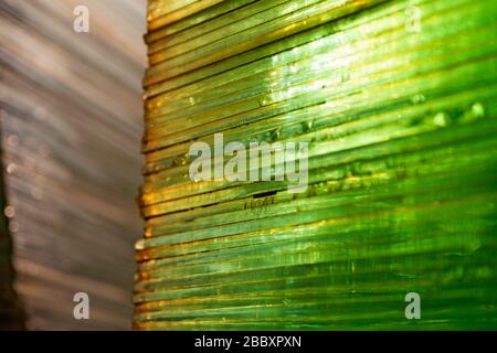 green glass sheets stacked on top of each other with sunlight shining through them Stock Photo