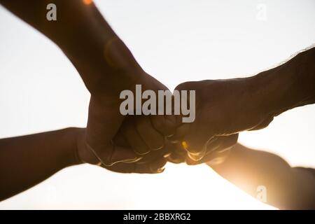 Close up bottom view of people giving fist bump showing unity and teamwork. Friendship happiness leisure partnership team concept. Stock Photo