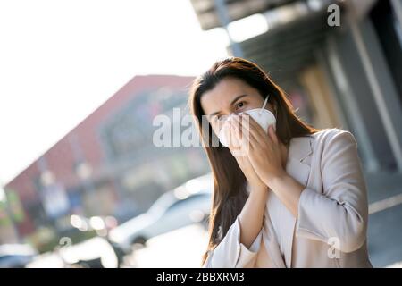 Close up of a businesswoman in a suit wearing Protective face mask and cough, get ready for Coronavirus and pm 2.5 fighting against beside road in bac Stock Photo