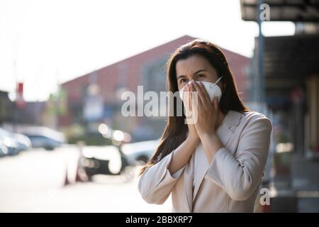 Close up of a businesswoman in a suit wearing Protective face mask and cough, get ready for Coronavirus and pm 2.5 fighting against beside road in bac Stock Photo