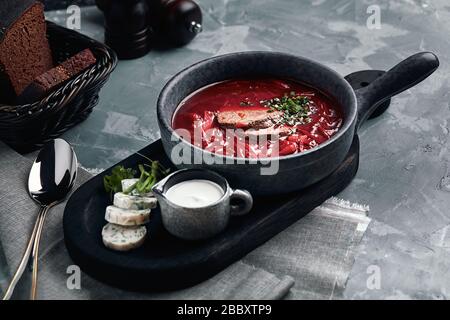 Hot soup. Borsch with red beans and braised beef. Comfortable food. Serving with brown bread and pork fat in a rustic style. Stock Photo