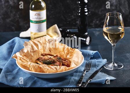 Fillet of white fish pollock, cod, sea bass, sea bream with olives, tomatoes and lemon, baked in parchment. Traditional italian food fish papillo with Stock Photo