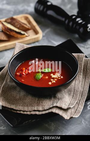 Tomato soup in a black bowl on a gray stone background. View from above. Copy space. Gray background. calm light. Food concept Stock Photo