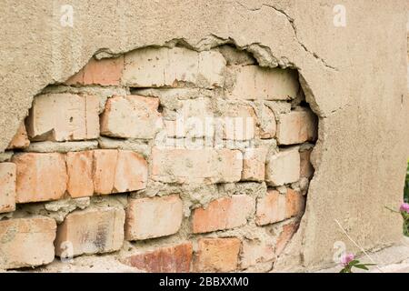 Non technology plaster. Building cracked plaster facade wall with brick. Stock Photo