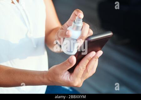 Woman Cleaning And Disinfecting Cell Phone Against Virus Stock Photo