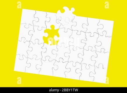 Blank White Puzzle with one piece missing isolated on yellow Stock Photo