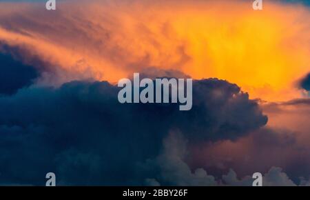 Dramatic stormy heaven moody ominous cloudscape at hurricame skies, aggressive dangerous disaster storm in atmospehre, orange sunset, cloudy rainy sky. Stock Photo