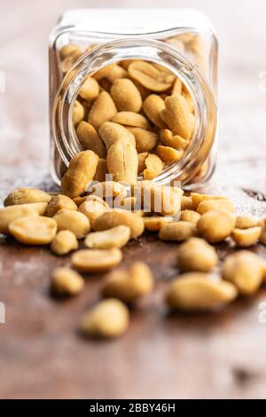 Roasted salted peanuts. Crispy nuts in jar on wooden table. Stock Photo