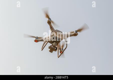 Modern RC Drone / Quadcopter with camera flying in a bright and clear blue sky. New technology in the aero photo shooting. Stock Photo