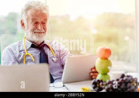Professional nutrition health advisor doctor happy working at office desk with fruit apple and grape recommend to eat for healthy. Stock Photo