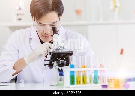 Asian Scientist Doctor working in medical healthcare lab for science medicine research looking at microscope Stock Photo