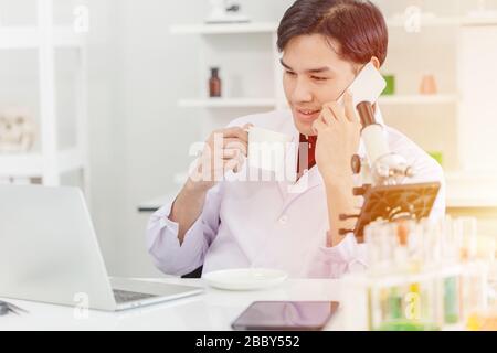 scientist relax working in the morning check the e-mail drink hot coffee and calling with friend Stock Photo