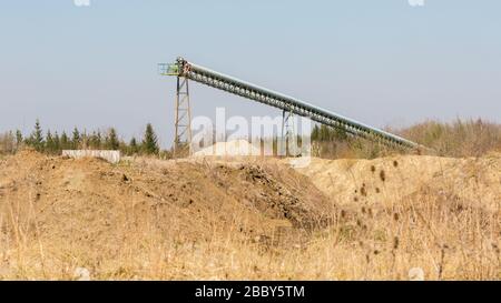 Conveyor belt of a sand and gravel plant close to Munich. Hills with soil in the foreground. Sand & gravel mining industry. 16:9 panorama format. Stock Photo