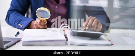 Closeup Of Auditor Scrutinizing Financial Documents At Desk In Office Stock Photo