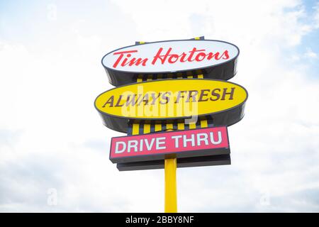 Sign showing Tim Hortons fast food restaurant logo and slogan with sky background