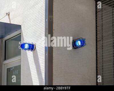 Two blue caution safety lights on corner of building outside Stock Photo