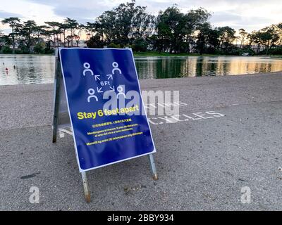 Coronavirus COVID-19 social distancing signboard warning people to stay six feet apart in front of lake Stock Photo