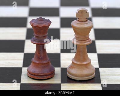 Chess black queen and white king stand on a wooden chessboard Stock Photo