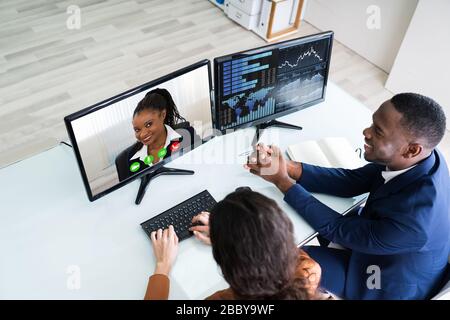 Side View Of Businesswoman And Businessman Video Conferencing With Colleague On Computer In Office Stock Photo