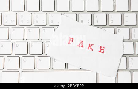 Word Fake written on torn paper on a computer keyboard Stock Photo