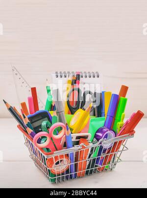 School supplies in a shopping basket, natural wood background. Back to school concept Stock Photo