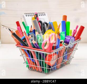 School supplies in a shopping basket, natural wood background. Back to school concept Stock Photo