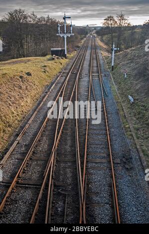 Aerial view over twin railway tracks heading into the distance through rural countryside landscape Stock Photo