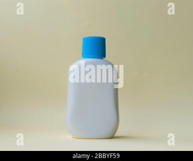 White plastic bottle for cream or oil on the yellow background. Stock Photo