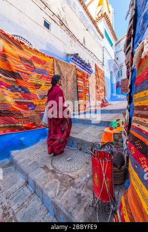 Chefchaouen, Morocco: a woman in red walking in the Medina Stock Photo