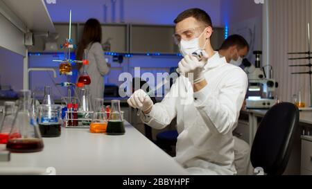 Young scientist mixing colored liquids in a flask. Stock Photo