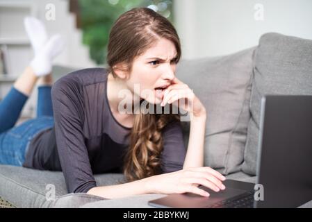 Young woman scared in front of laptop at home Stock Photo