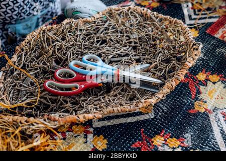 Handmade weave basket with scissors on table. Craft workshop. Close up shot. Stock Photo