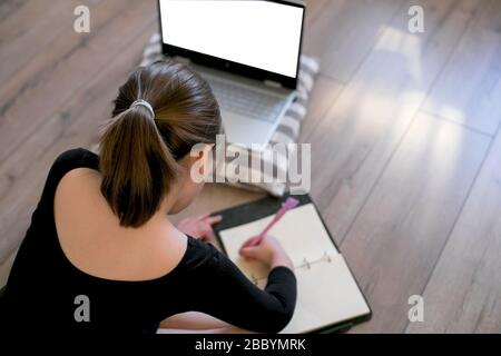 Schoolgirl studying at home using laptop. Online education, home education, quarantine, stay at home concept. Mockup concept. Stock Photo