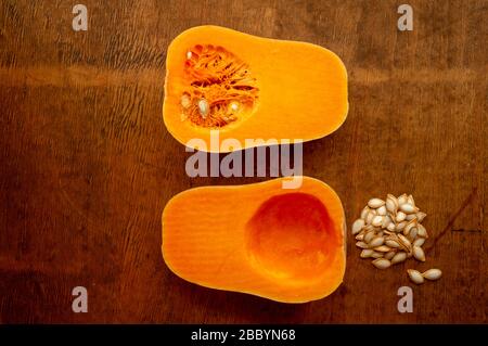 Two halves of sliced ripe butternut squash with seeds on rustic wooden tabletop from above Stock Photo