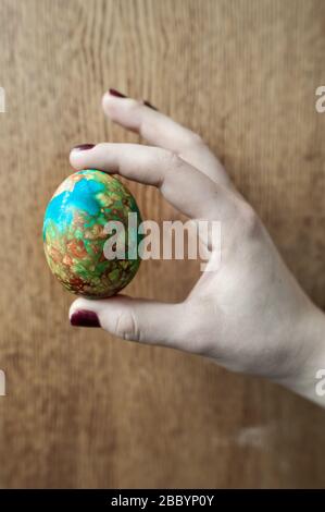 A hard boiled, beautifully decorated Easter Egg in a woman's hand.