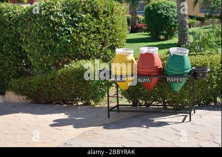 Three containers for garbage sorting and recycling. Yellow, red, green marks on garbage containers for paper, glass, plastic on beach in hotel Stock Photo