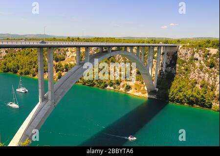 Automobile long high arched bridge over the Krka river in Croatia near Sibenik. Picturesque Croatian river landscape in spring and summer, Europe Stock Photo