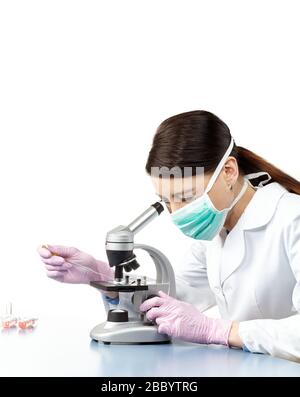 Woman wearing safety gloves and mask doing research with microscope in a laboratory, isolated on white. Stock Photo