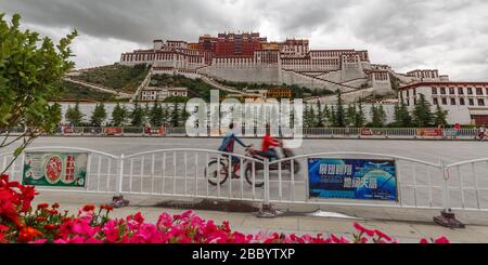 Panorama view of Potala Palace. A motorcycle and a bicycle are passing by in the foreground. The palace was built in the 17th century. Stock Photo