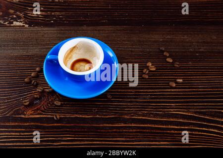 Dirty blue cup after coffee on a wooden table. Near to the cup are coffee beans.  Stock Photo