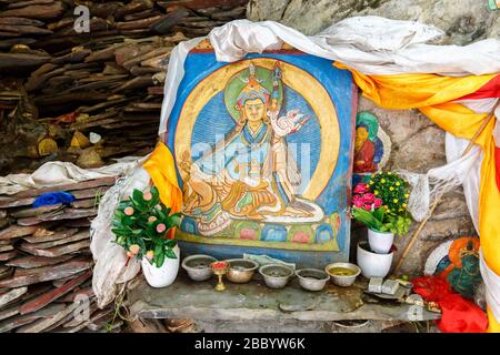 Colorful painting of a deity of tibetan buddhism. Placed outdoors in an area close to Potala Palace. With flowers and other offerings. Tibetan art. Stock Photo